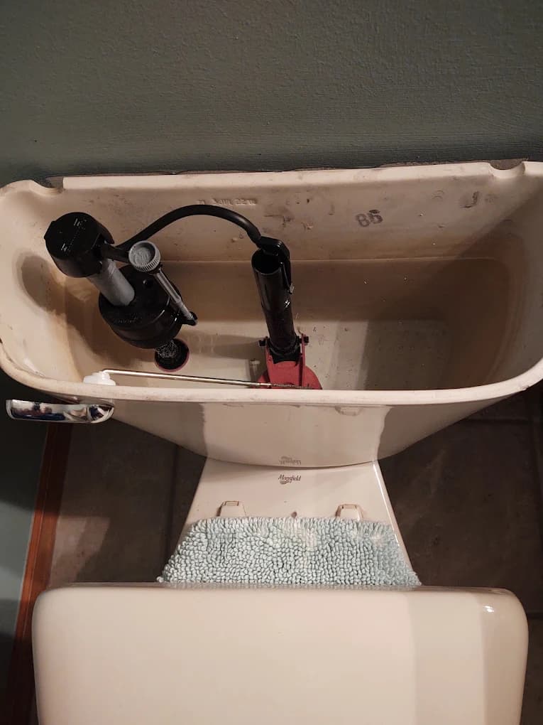 Inside a toilet tank showing the fill valve and flapper — common toilet repair parts in Milford